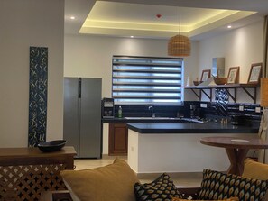 A modern kitchen with a built-in refrigerator, a sink, and a dining area with a table and chairs. - Nana in Diani’s  cozy 1bed luxury apartment w/beach,pool access! (Kwale County)