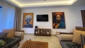Ein modernes Wohnzimmer mit Deckenventilator, zwei Sofas, einem Couchtisch und drei Bildern an der Wand.