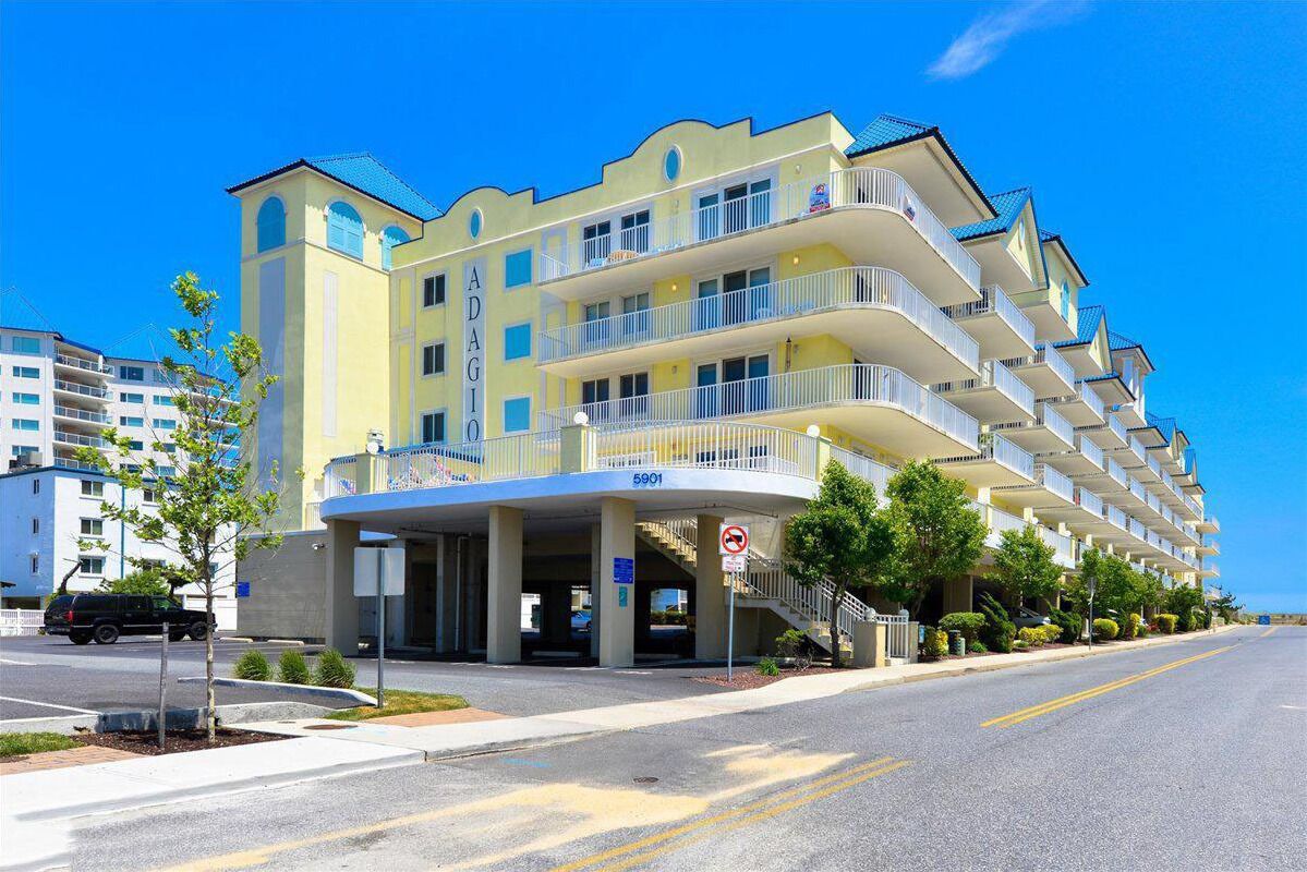 A multi-story hotel with a yellow facade, balconies, and a clear blue sky.