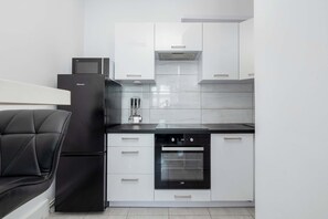 Eine moderne Küche mit weißen Schränken, einem schwarzen Kühlschrank, einer Mikrowelle und einem eingebauten Backofen.