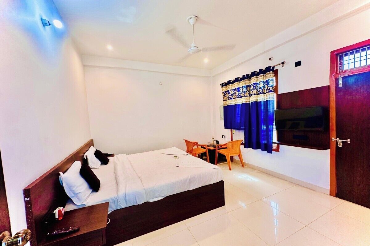 Une chambre d’hôtel comprenant un lit, un bureau avec une chaise, un ventilateur de plafond et un téléviseur.