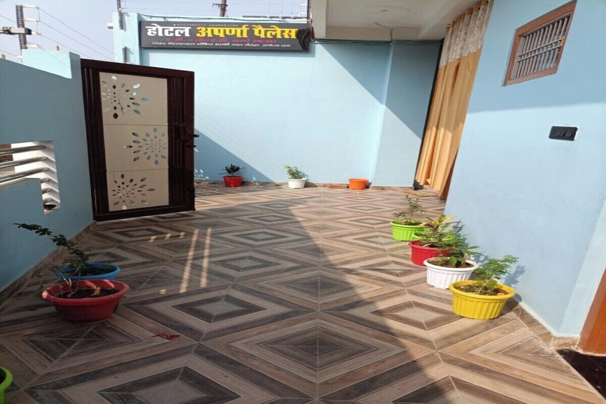 Un corridoio d'albergo con pavimento decorato, piante in vaso e una porta chiusa.