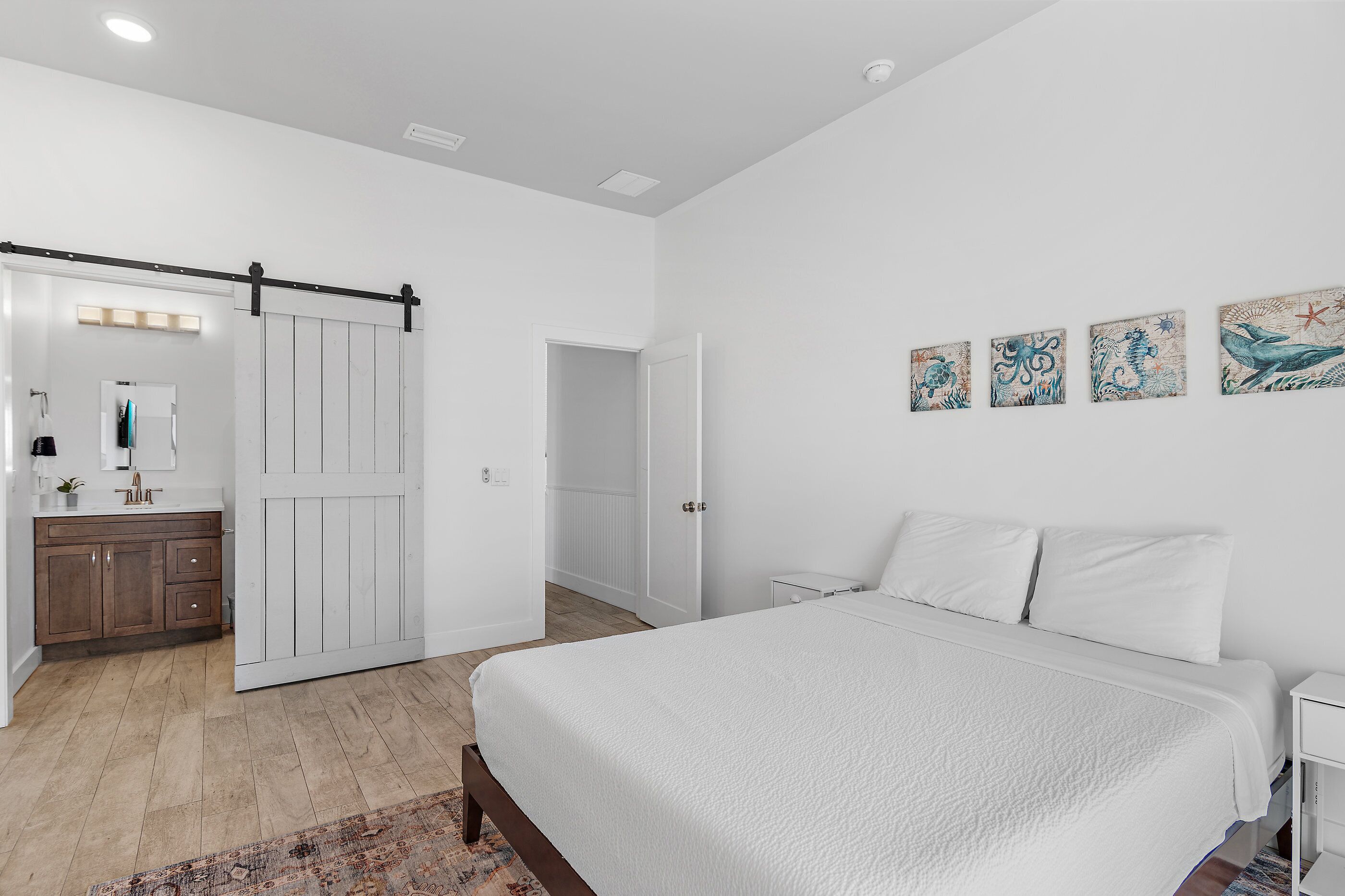 Un dormitorio con una cama grande, un armario, un espejo y obras de arte en la pared.
