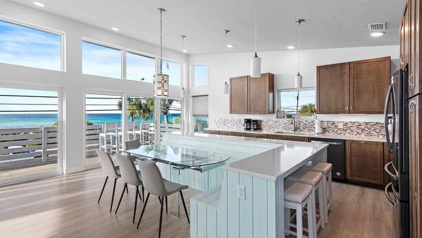 A modern kitchen with a large island, white cabinetry, and a view of the ocean. - 6BR Gulf-Front w/ Private Beach & Pool (Panama City Beach)