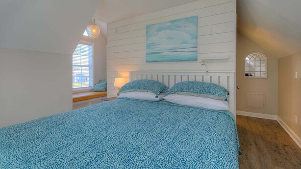 Une chambre à coucher avec un lit, une fenêtre, un tableau et une porte.