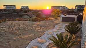 Een pand aan het strand met een patio, een grindpad, een jacuzzi en een trap naar een terras.