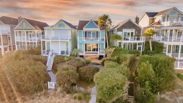 A coastal residential area with houses featuring balconies and a pathway leading to a central building. - High Tide | Oceanfront 3BR with Pool & Beach Access | Ocean Point (Isle of Palms)