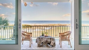 A balcony with wicker chairs, a table, and a view of the beach. - High Tide | Oceanfront 3BR with Pool & Beach Access | Ocean Point (Isle of Palms)