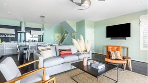 A modern living room with a grey sofa, a coffee table, and a TV mounted on the wall. - High Tide | Oceanfront 3BR with Pool & Beach Access | Ocean Point (Isle of Palms)