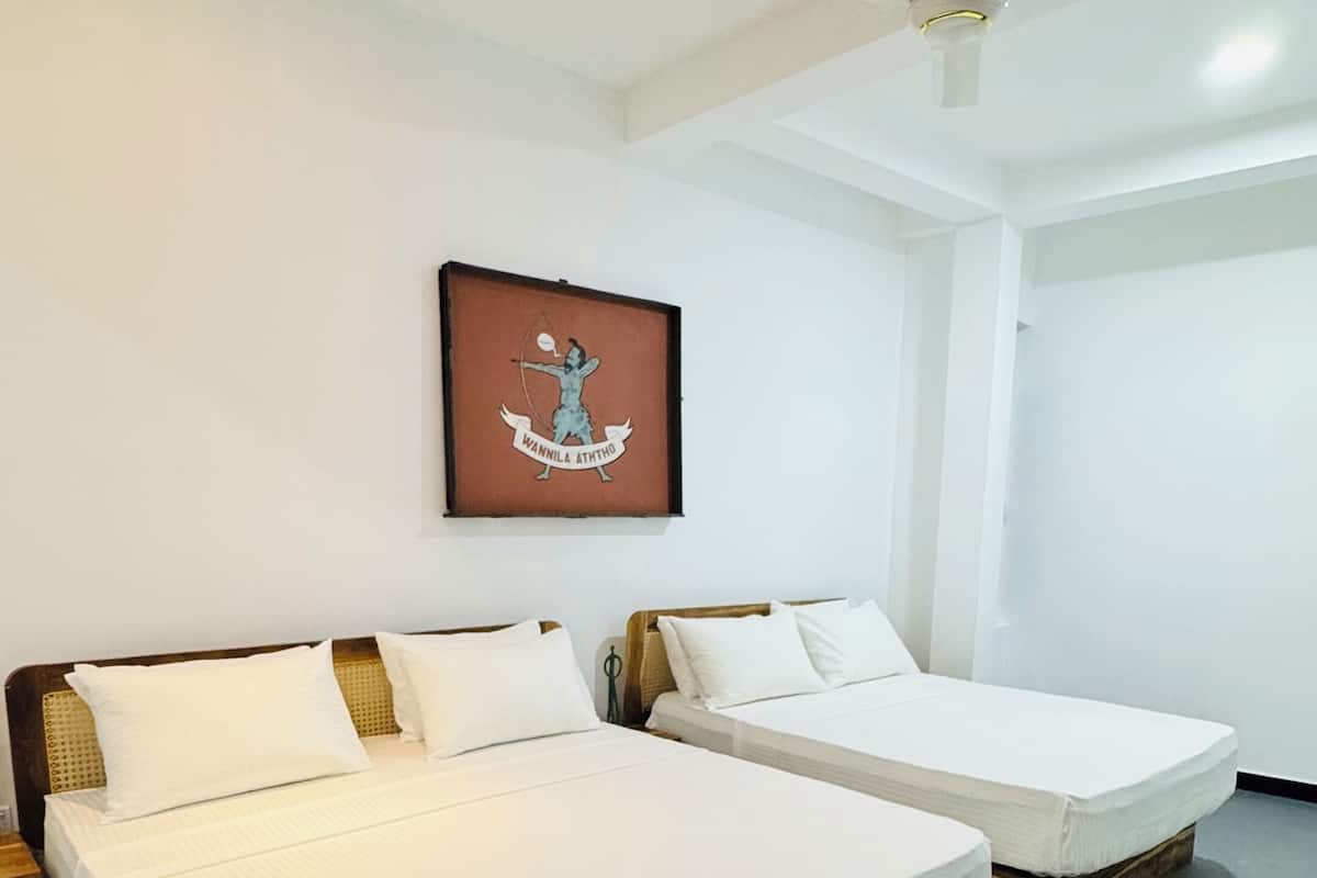 A hotel room with two beds, a ceiling fan, and a framed picture on the wall.