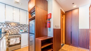 Una cucina moderna con forno integrato, frigorifero in acciaio inossidabile e un'unità scaffali in legno.