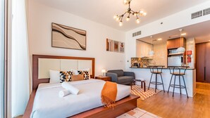 Camera d'albergo moderna con un letto grande, un piccolo divano, angolo cottura e zona pranzo.