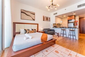 Ein modernes Hotelzimmer mit einem großen Bett, einer kleinen Sitzecke, einer Küchenzeile und einem Essbereich.