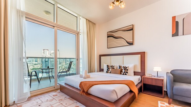 Una camera d'hotel moderna con un letto grande, un balcone vista città, un tavolino e una sedia.