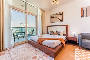 Une chambre d’hôtel moderne avec un grand lit, un balcon offrant une vue sur la ville, une petite table et une chaise.