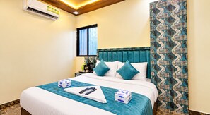 A hotel room with a bed, a nightstand, a window, and a patterned curtain. - Hotel Versova Inn (Mumbai)