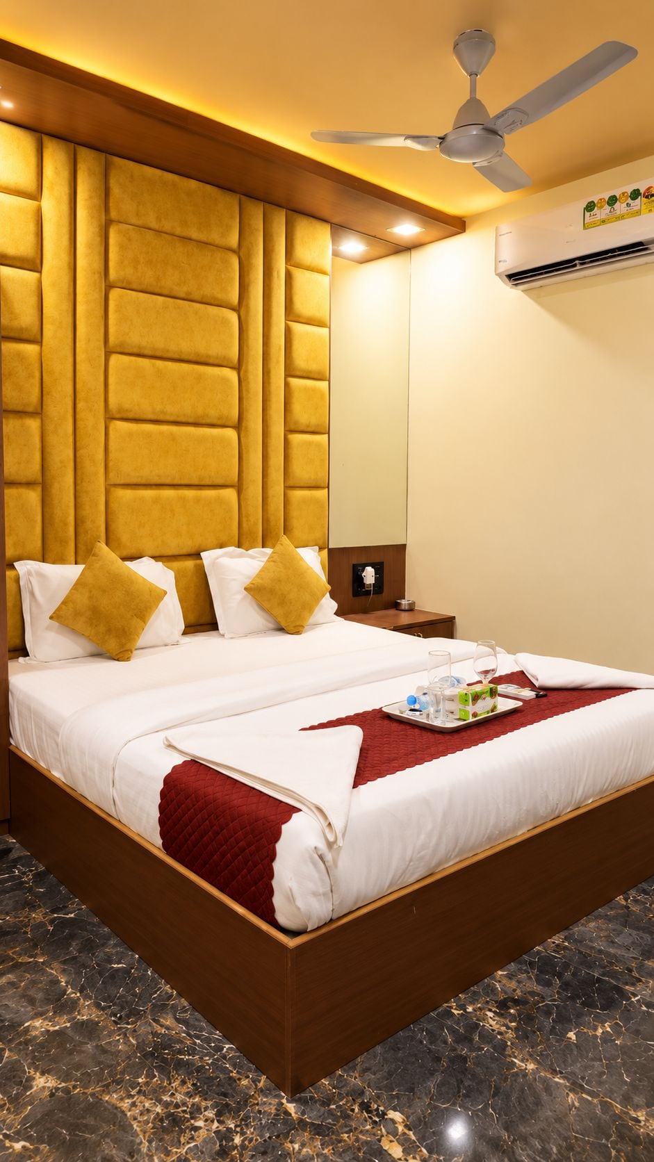 Una habitación de hotel con una cama grande, un ventilador de techo y un equipo de aire acondicionado.