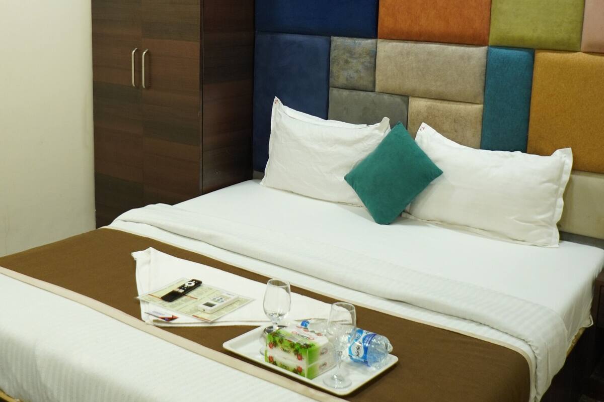 Ein Hotelzimmer mit Bett, einem Holzschrank, einem Kopfteil mit farbigem Wandpaneel und einem Marmorboden.
