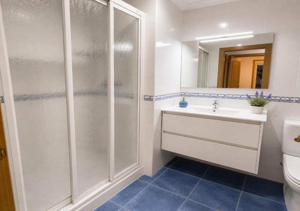 Un baño con ducha, lavabo, espejo e inodoro.