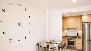 A modern kitchen with a stainless steel refrigerator, wooden cabinets, and a dining area with a table set for four. - APARTMENT WITH SEA VIEW (Viveiro)