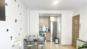 A modern kitchen with stainless steel appliances, a dining area with a table and chairs, and a living space with a sofa. - APARTMENT WITH SEA VIEW (Viveiro)