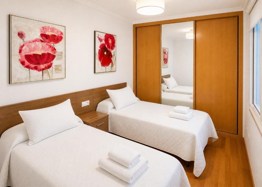 Une chambre d’hôtel avec deux lits, une tête de lit en bois, une armoire et des œuvres d’art accrochées aux murs.
