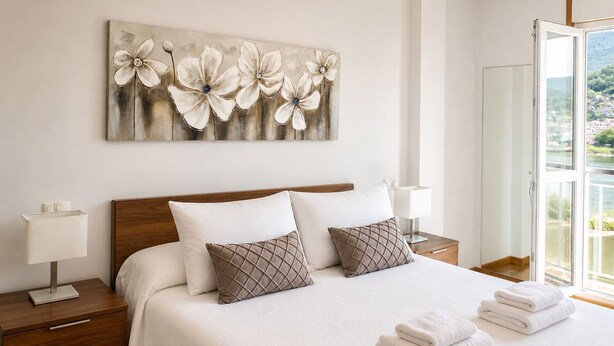 A hotel room with a bed, two bedside tables, a nightstand, a window with a view, and a wall-mounted artwork. - APARTMENT WITH SEA VIEW (Viveiro)