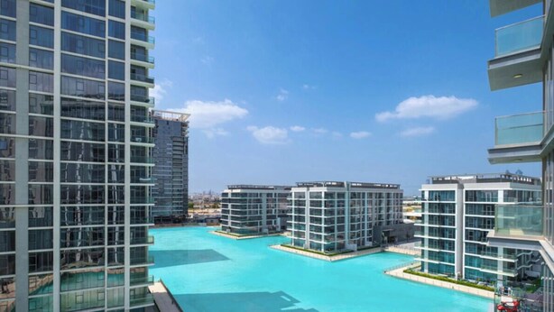 Un complejo moderno de edificios altos con un patio central y una piscina.
