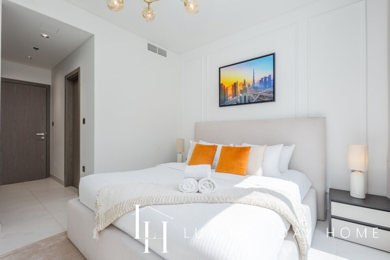 Une chambre moderne avec un grand lit, du linge de lit blanc et un tableau représentant un paysage urbain accroché au mur.