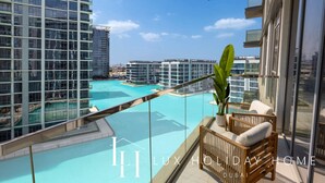 Un balcón con vista a una piscina, rodeado de edificios altos.