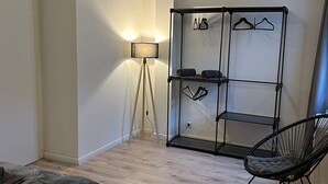 Ett sovrum med en säng, en stol, en garderob och en golvlampa.