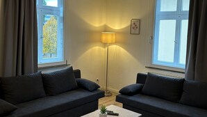 Ett modernt vardagsrum med två mörka soffor, ett ljust soffbord och en golvlampa.