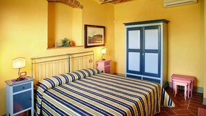 A room with a bed, a nightstand, a dresser, a small table, and a picture on the wall.