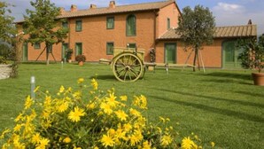 A traditional building with a large wheel, surrounded by a well-maintained lawn and flowering plants.
