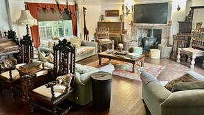 Un salón tradicional con muebles antiguos, una chimenea y un televisor grande.