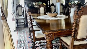 Un comedor tradicional con una gran mesa de madera, sillas ornamentadas y un rug con diseño.