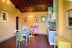 Una cucina con rivestimento in piastrelle, un fornello e un tavolo con sedie.