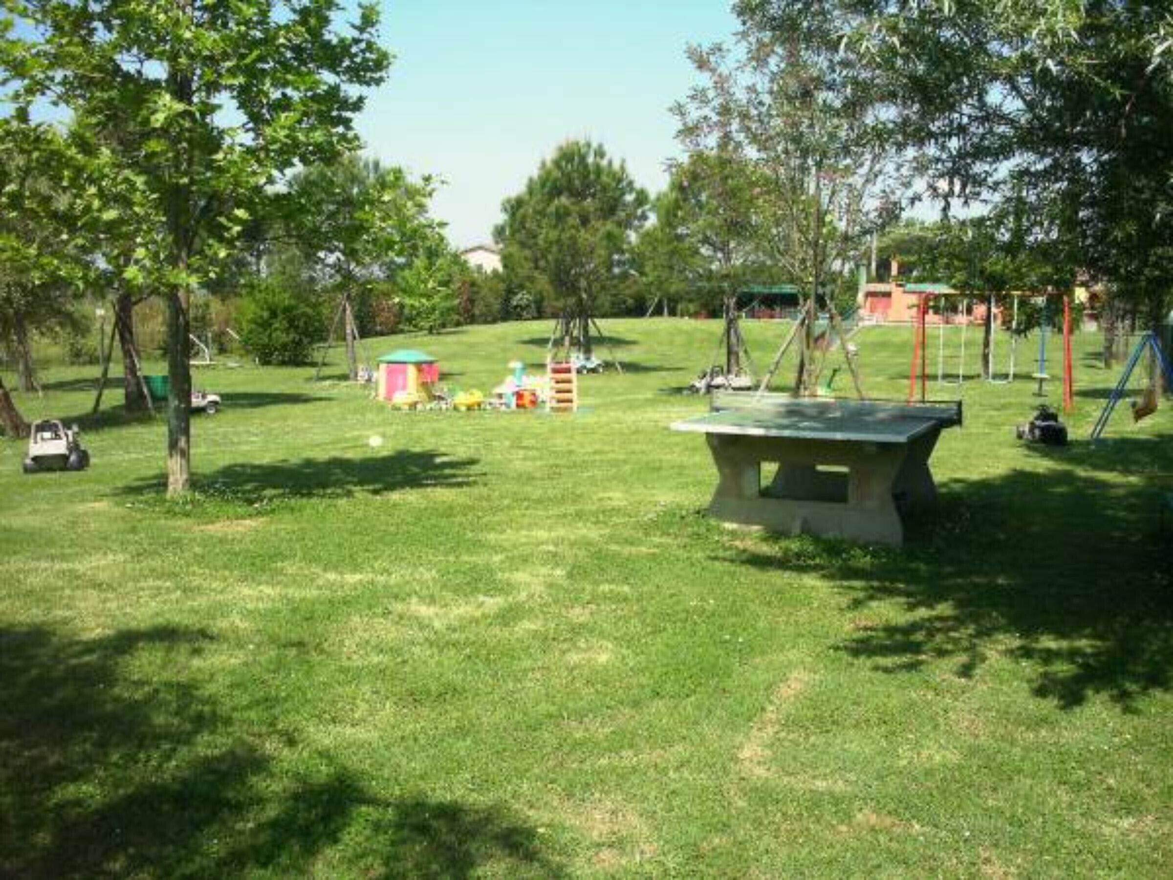 Un espace vert avec des aires de jeux pour enfants, une table de pique-nique et des arbres.