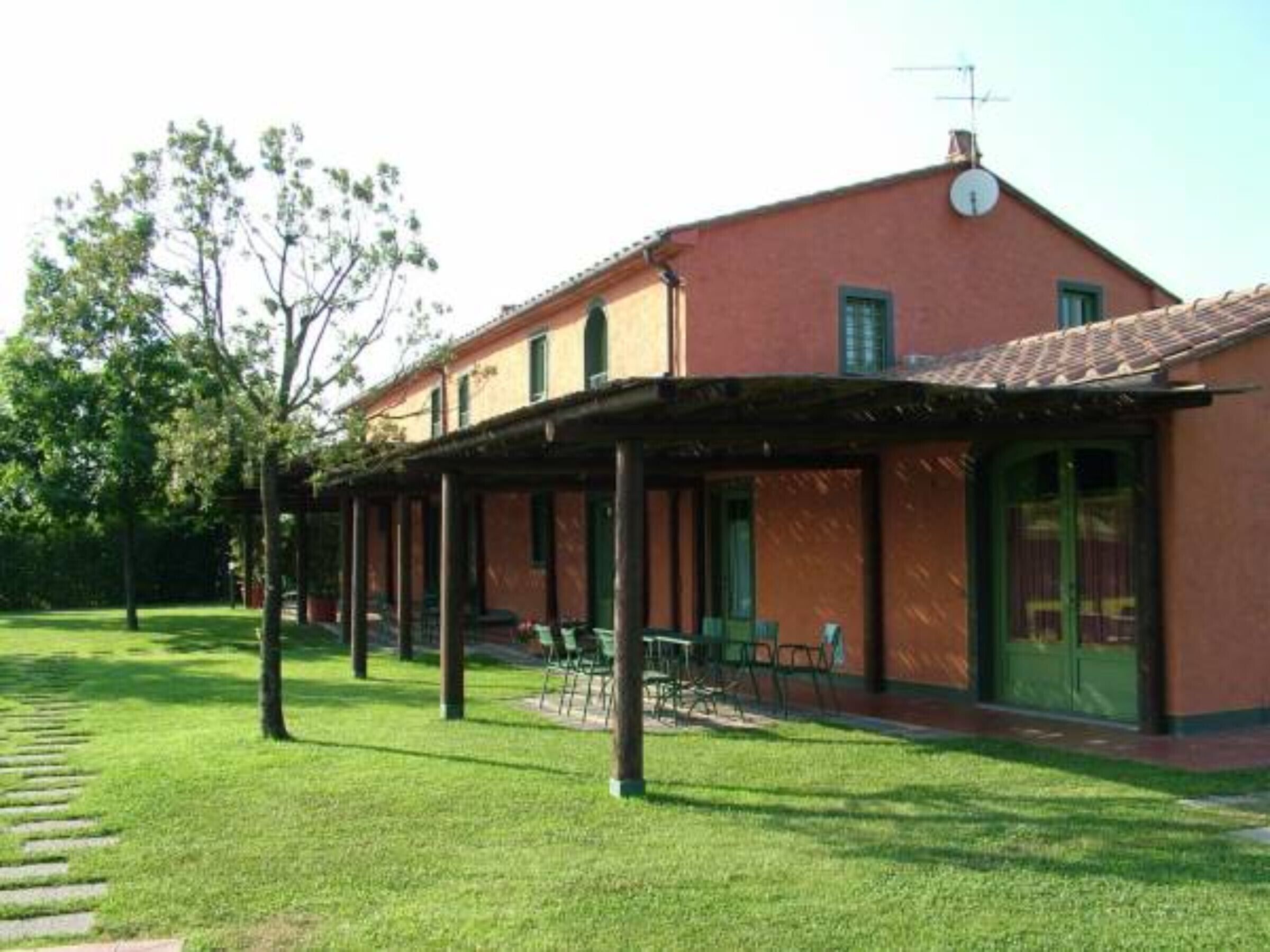 A building with a red facade, a covered patio area, and a lawn.