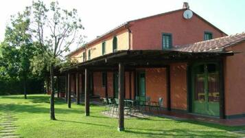 A building with a red facade, a covered patio area, and a lawn.