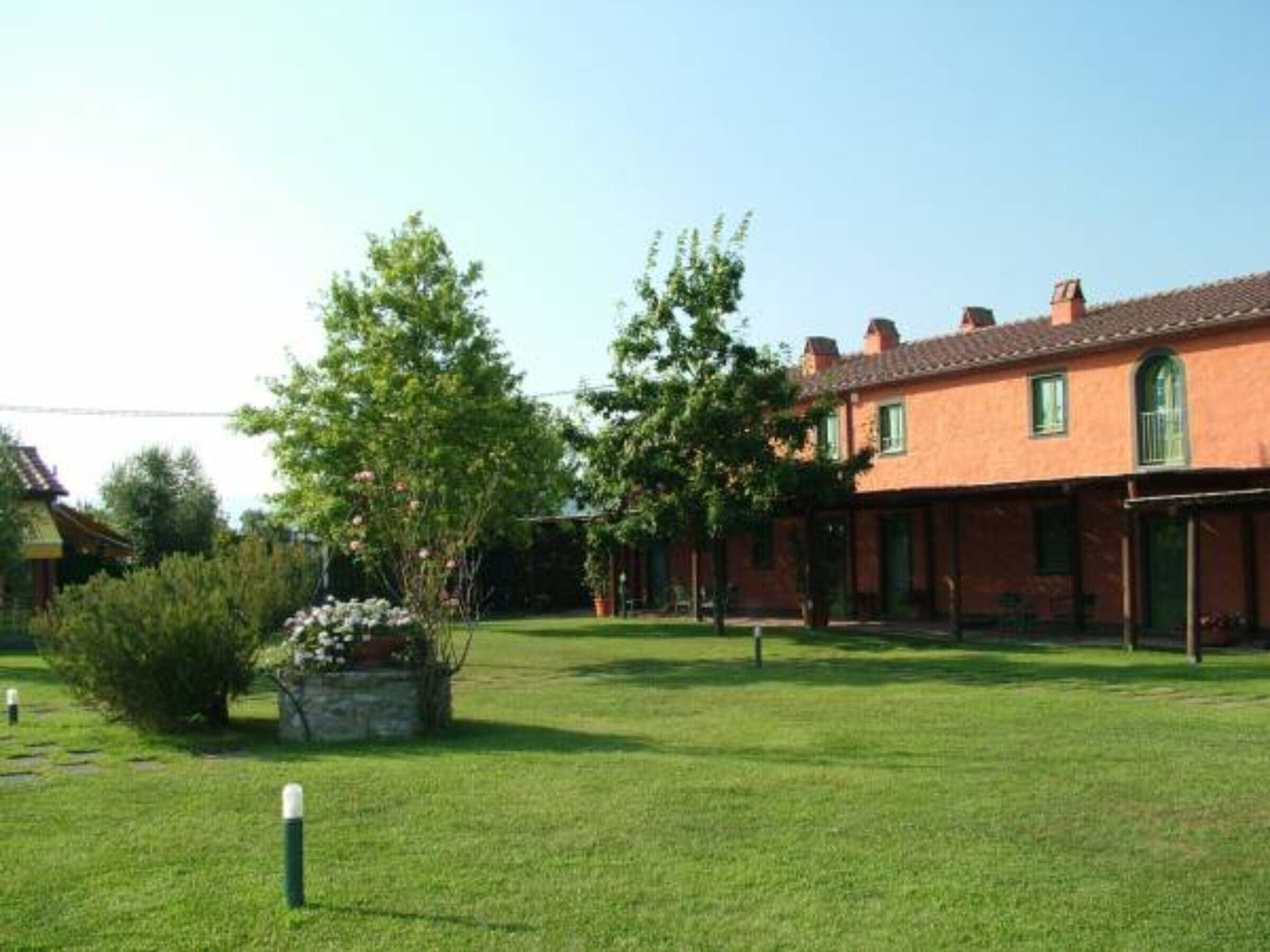 A traditional building with a tiled roof, surrounded by a well-maintained lawn and trees.