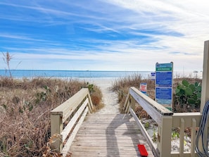 A wooden boardwalk leading to a beach with a clear sky. - Sea Marsh I 404 (North Myrtle Beach)
