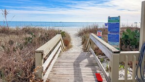 Pasarela de madera que conduce a una playa, con un letrero que indica 'No transite por las dunas' y la referencia 'North Myrtle Beach'.