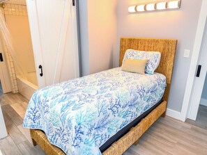 A bed with a woven headboard, a patterned bedspread, and a bedside lamp. - Sea Marsh I 404 (North Myrtle Beach)