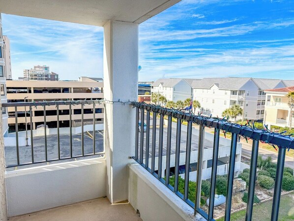 A balcony with a metal railing overlooking a parking area and residential buildings. - Sea Marsh I 404 (North Myrtle Beach)