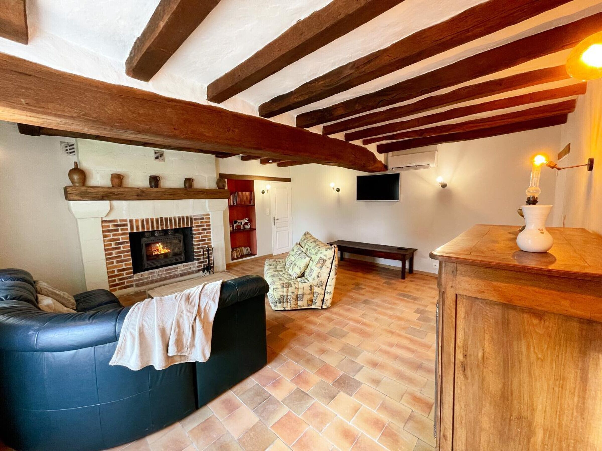 Una sala de estar acogedora con chimenea, un sofá de cuero, un sillón estampado y una mesa de centro de madera.