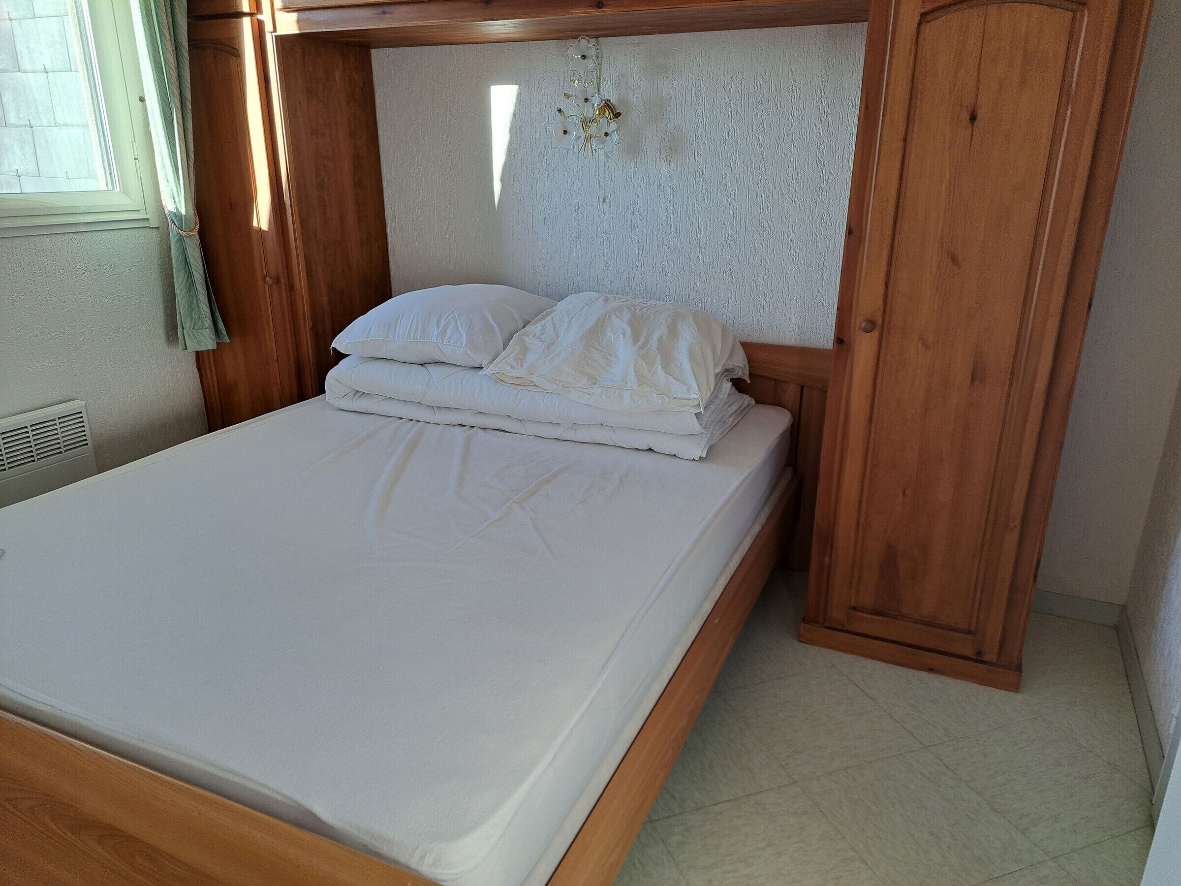 A single bed with a wooden headboard and a white mattress.