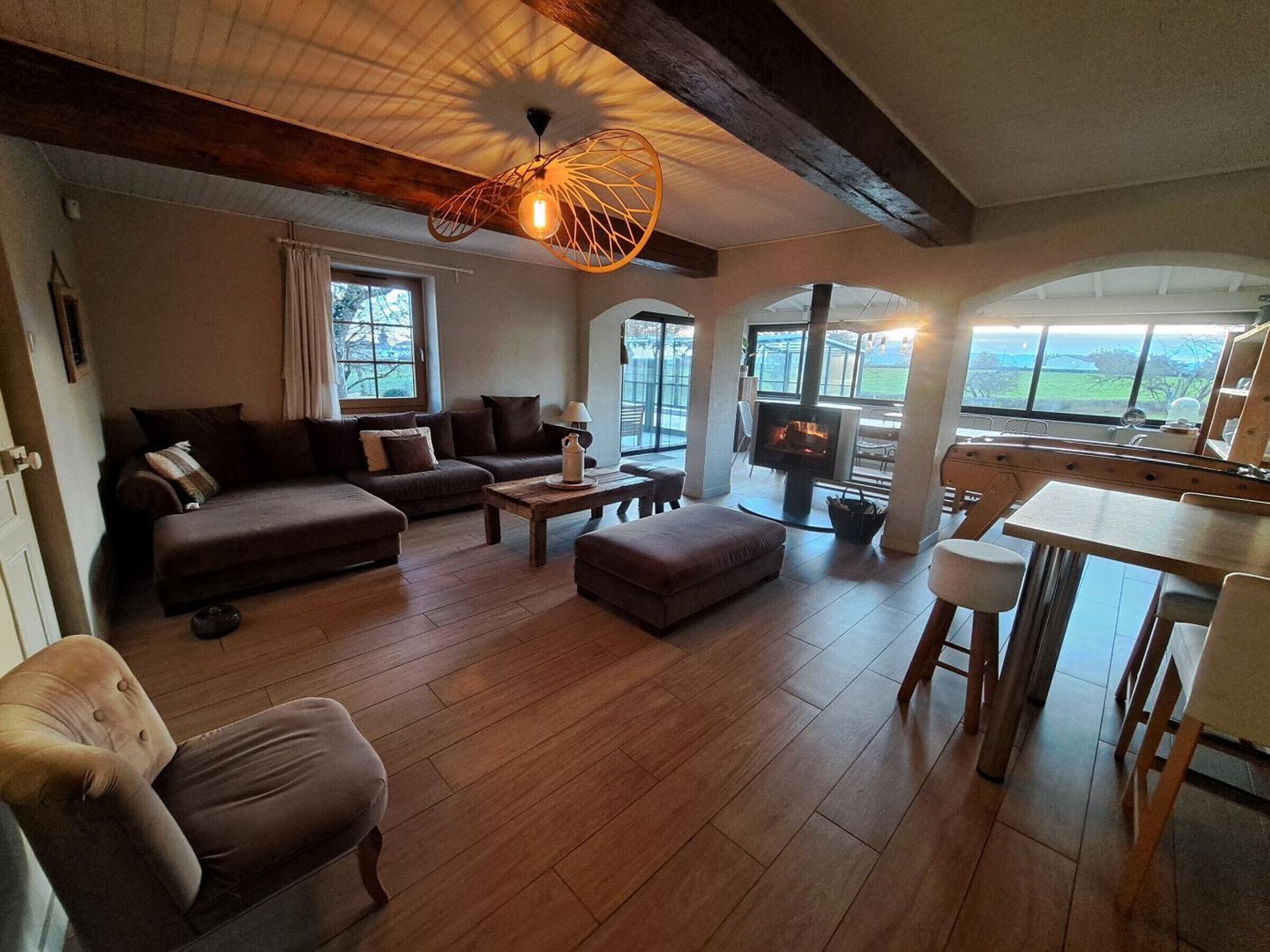 Un salón amplio con sofá, reposapiés y chimenea.