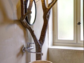 Une salle de bain avec un miroir en forme d’arbre, un lavabo et une fenêtre.