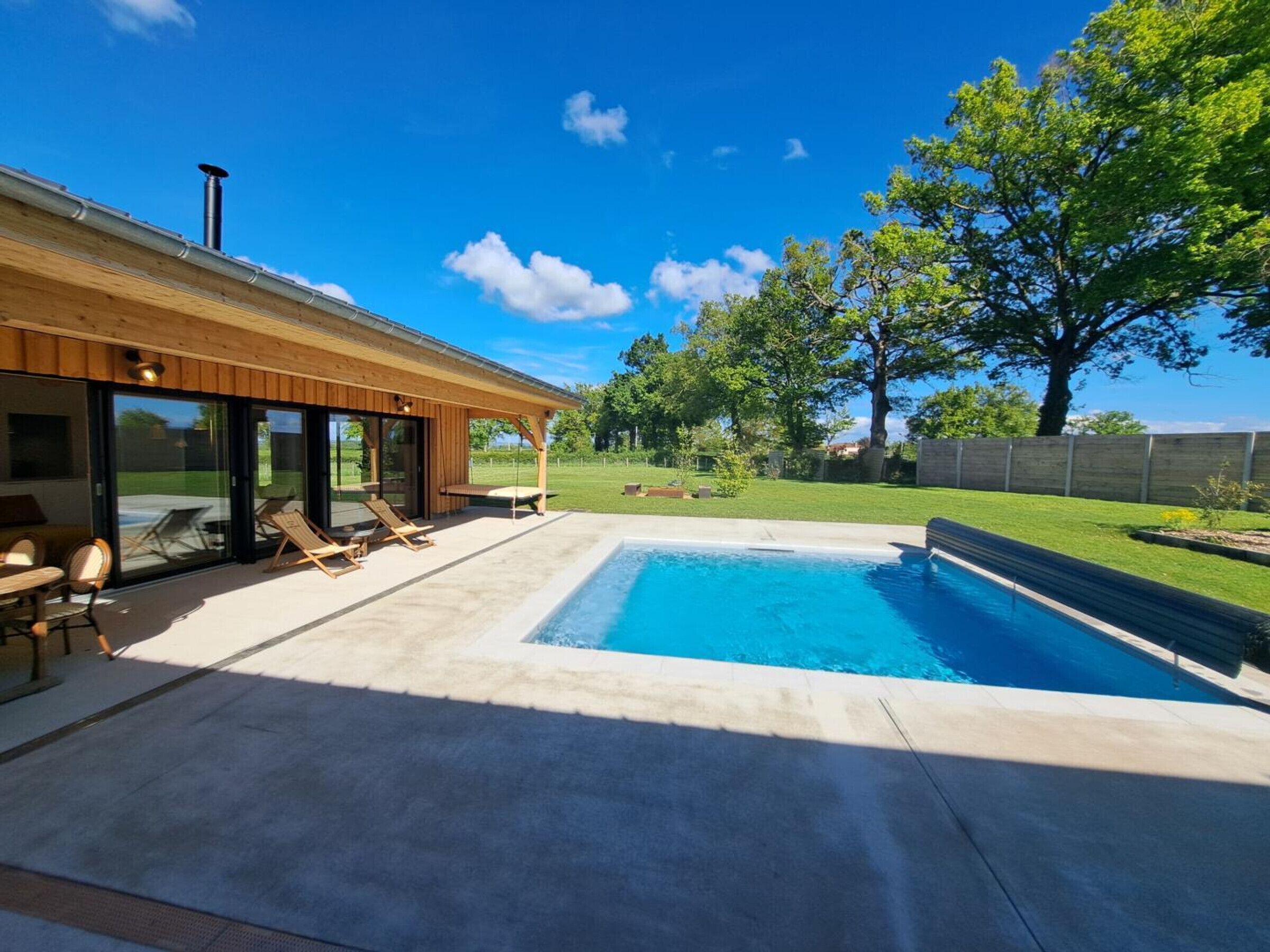 Una casa moderna amb piscina, mobiliari d'exterior i terrassa coberta.